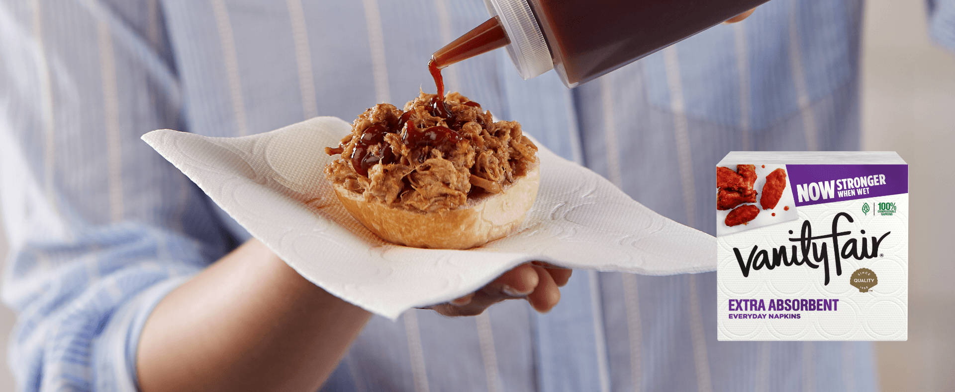 Person using a Vanity Fair Napkin to hold a barbecue pork sandwich.