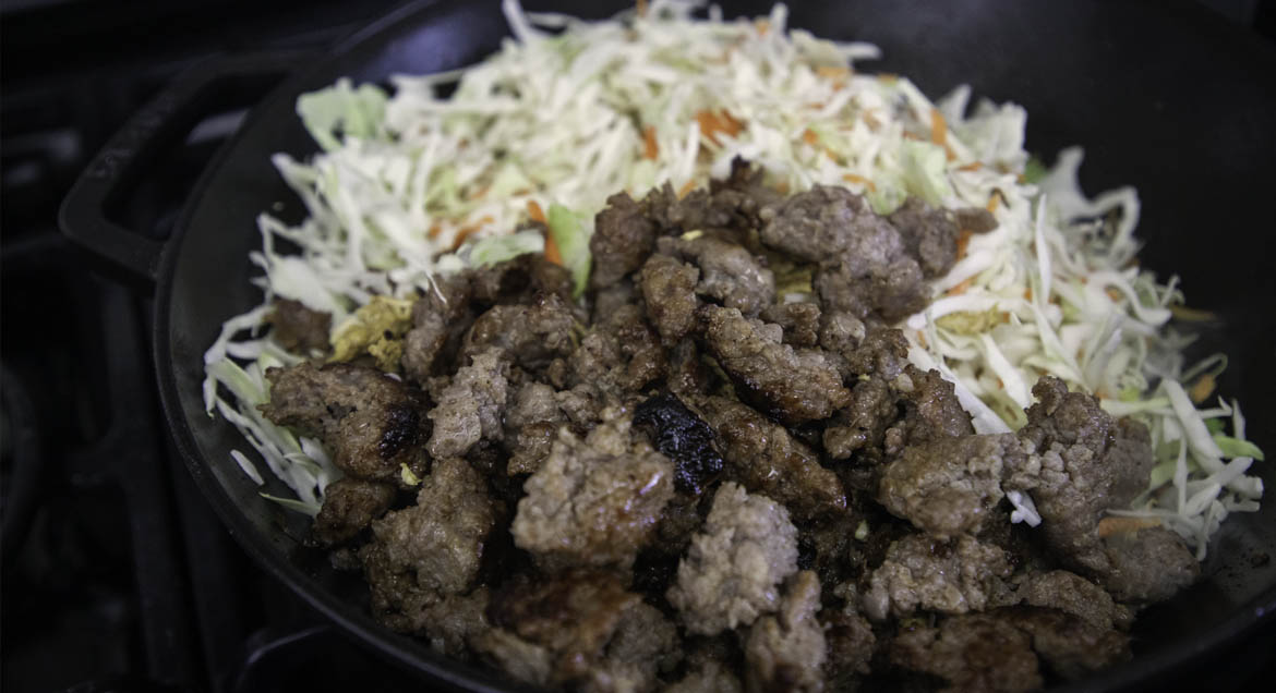 Ground Beef And Shredded Cabbage Cooking In Cast Iron Wok.