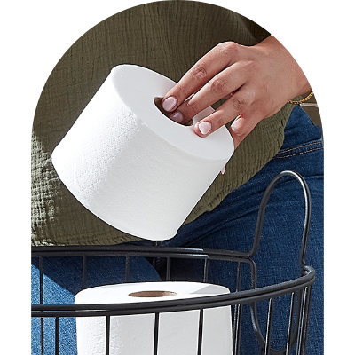 Hand placing toilet paper roll into basket.