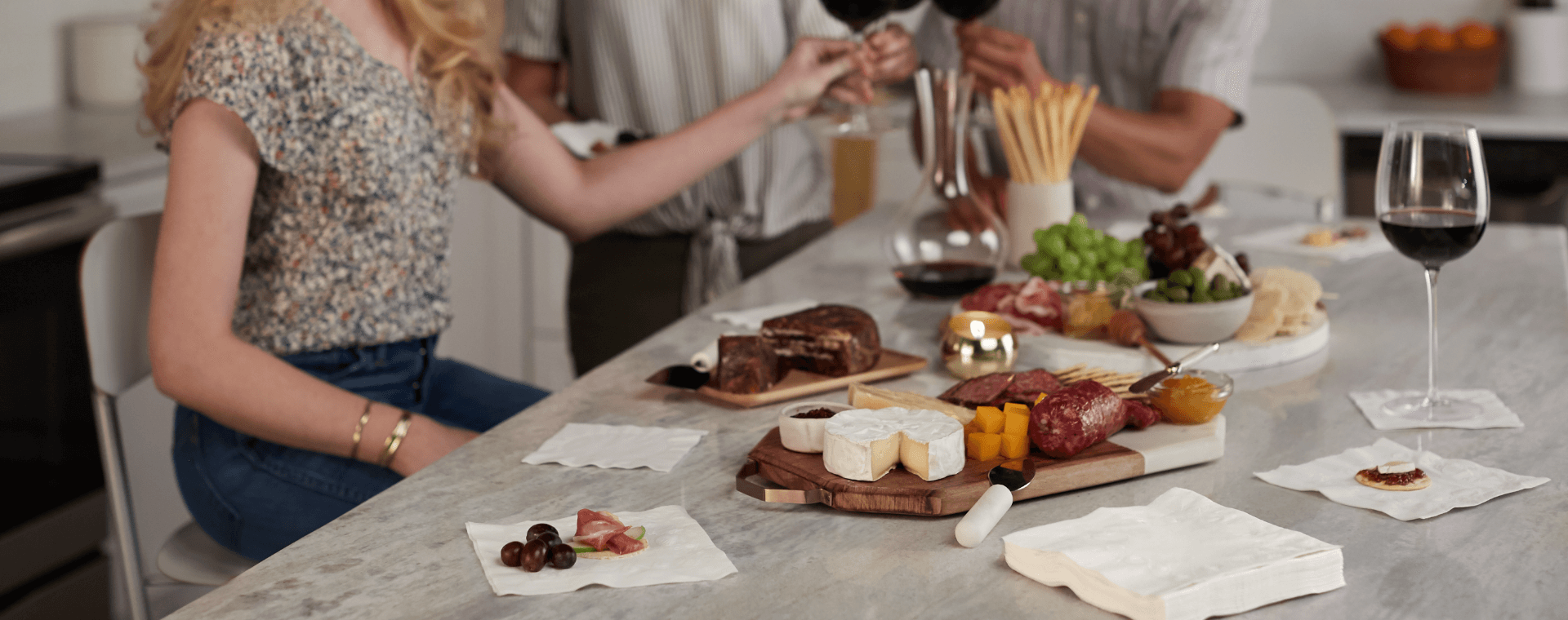 People gathered around a kitchen counter with food.